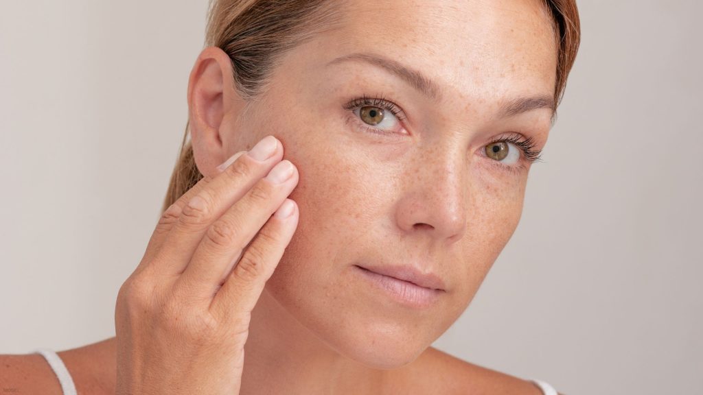 Woman examining her skin after mohs surgery (model)